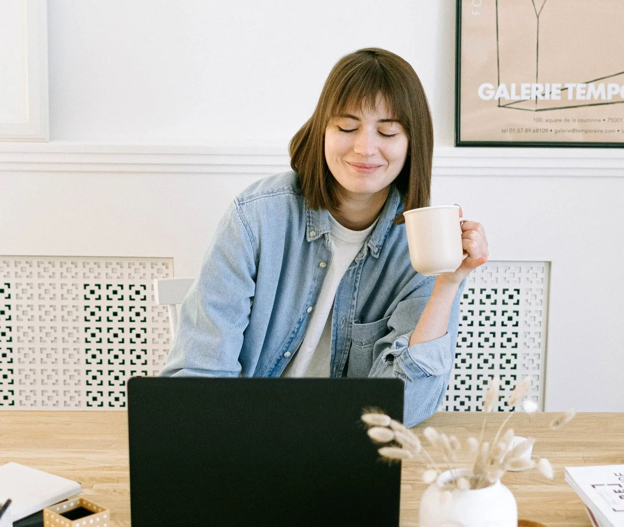woman smiling at her laptop drinking coffee